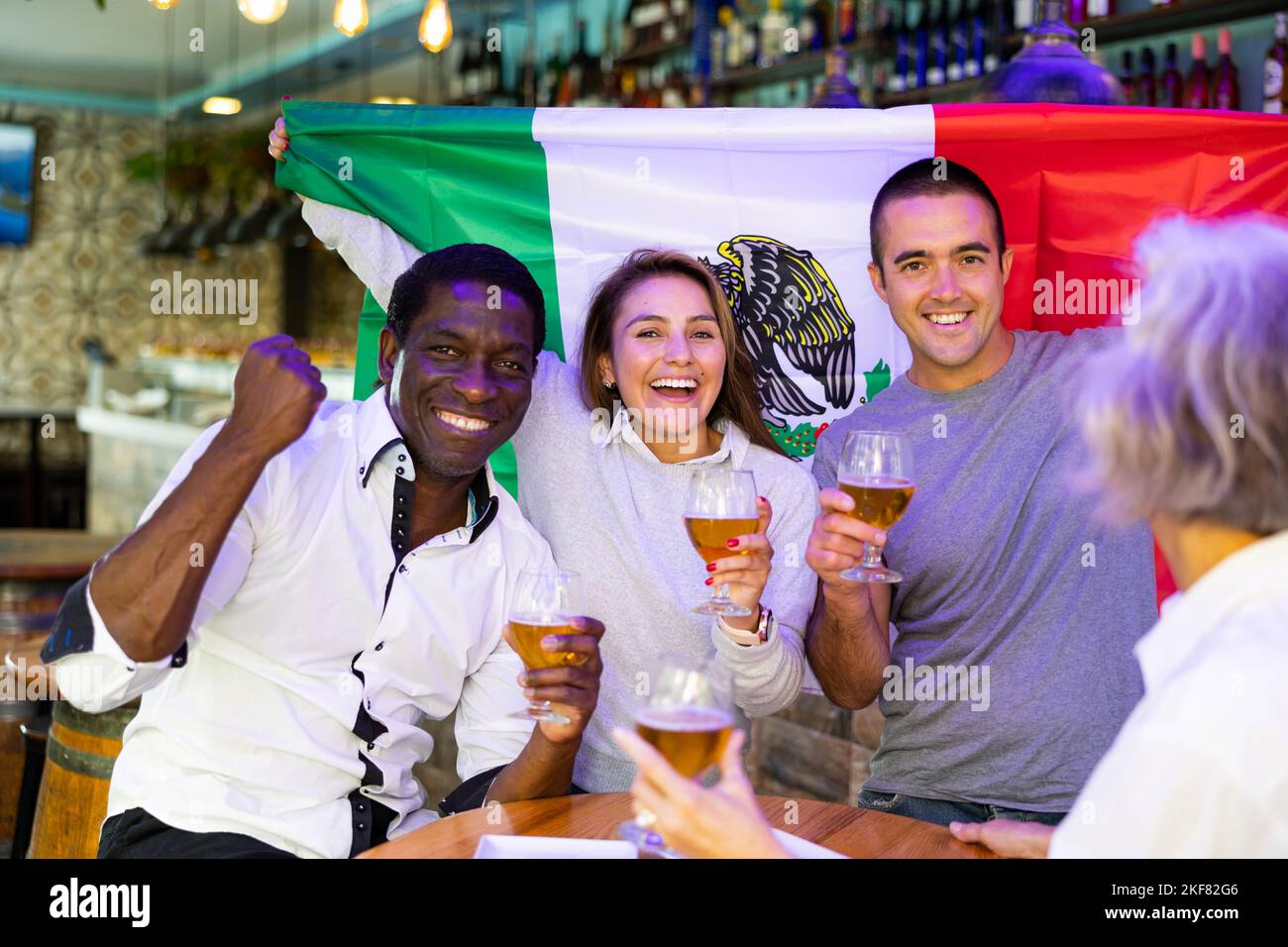 Joyful fans of the Mexican team celebrating the victory in night bar