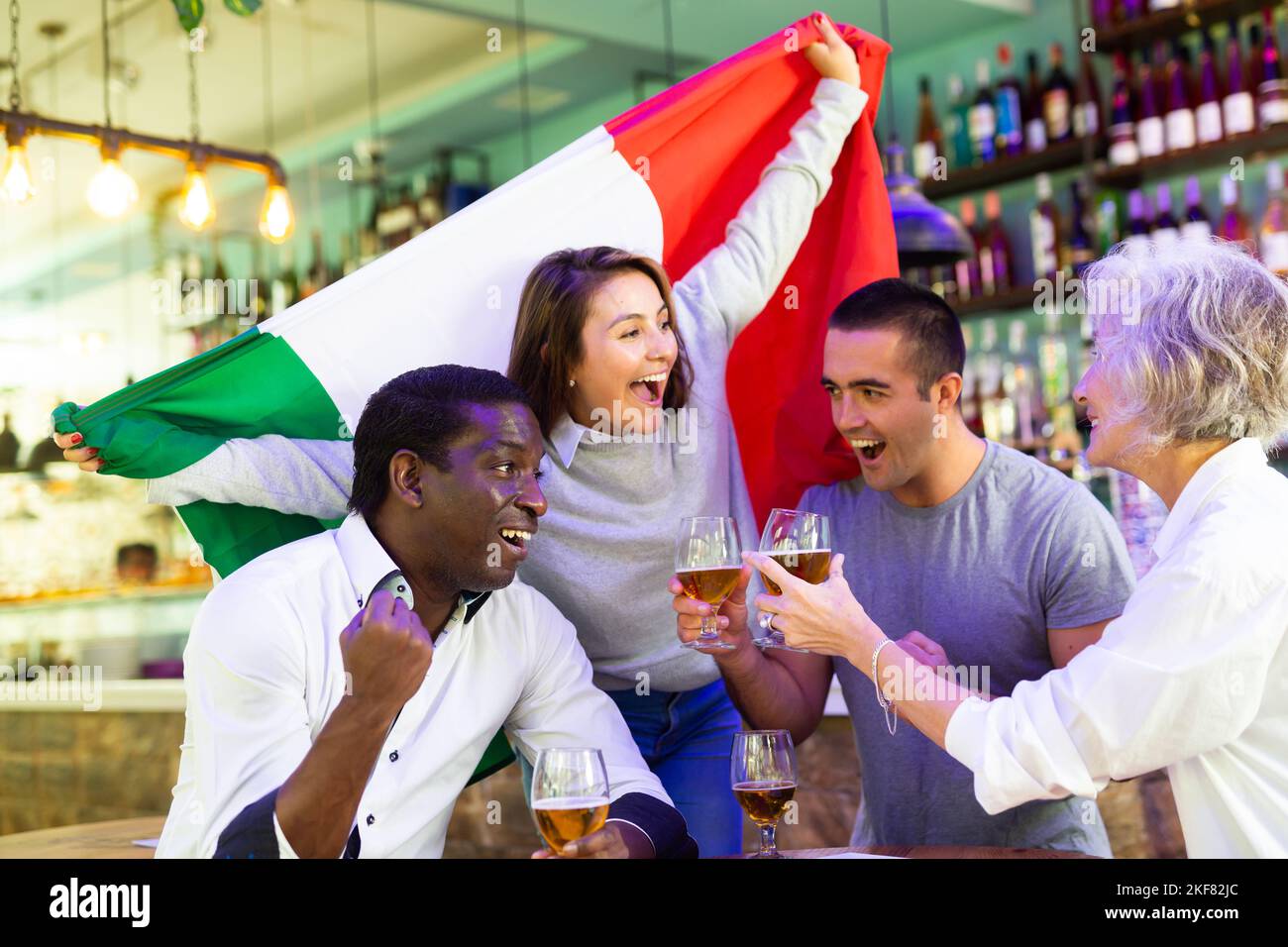 Cheerful international sport fans waving Italian flag and drinking beer