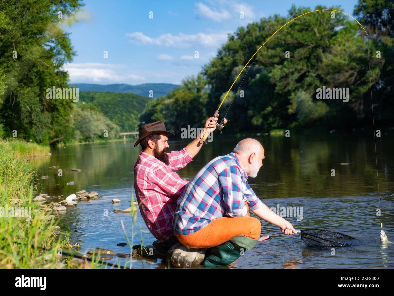 Two men friends fisherman fishing on river. Old father and son with rod ...