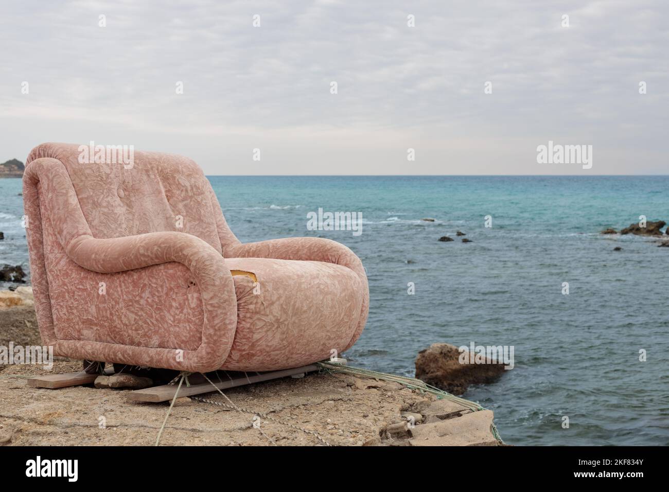 An old armchair on the shore of the beach, surrealistic scenery. Stock Photo