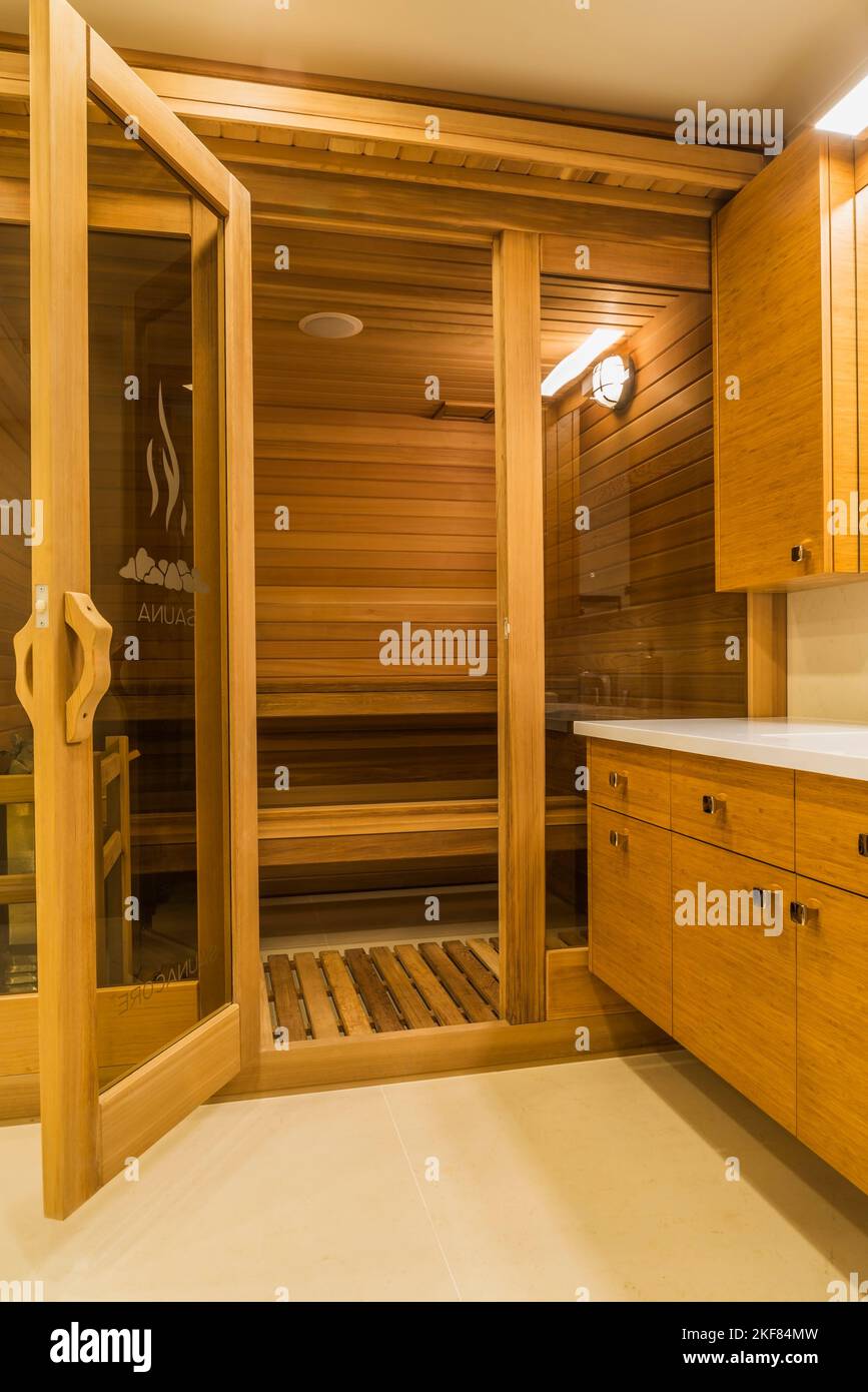Sauna room in basement bathroom with bamboo wood vanity and white marble floor inside luxurious stained cedar and timber wood home. Stock Photo