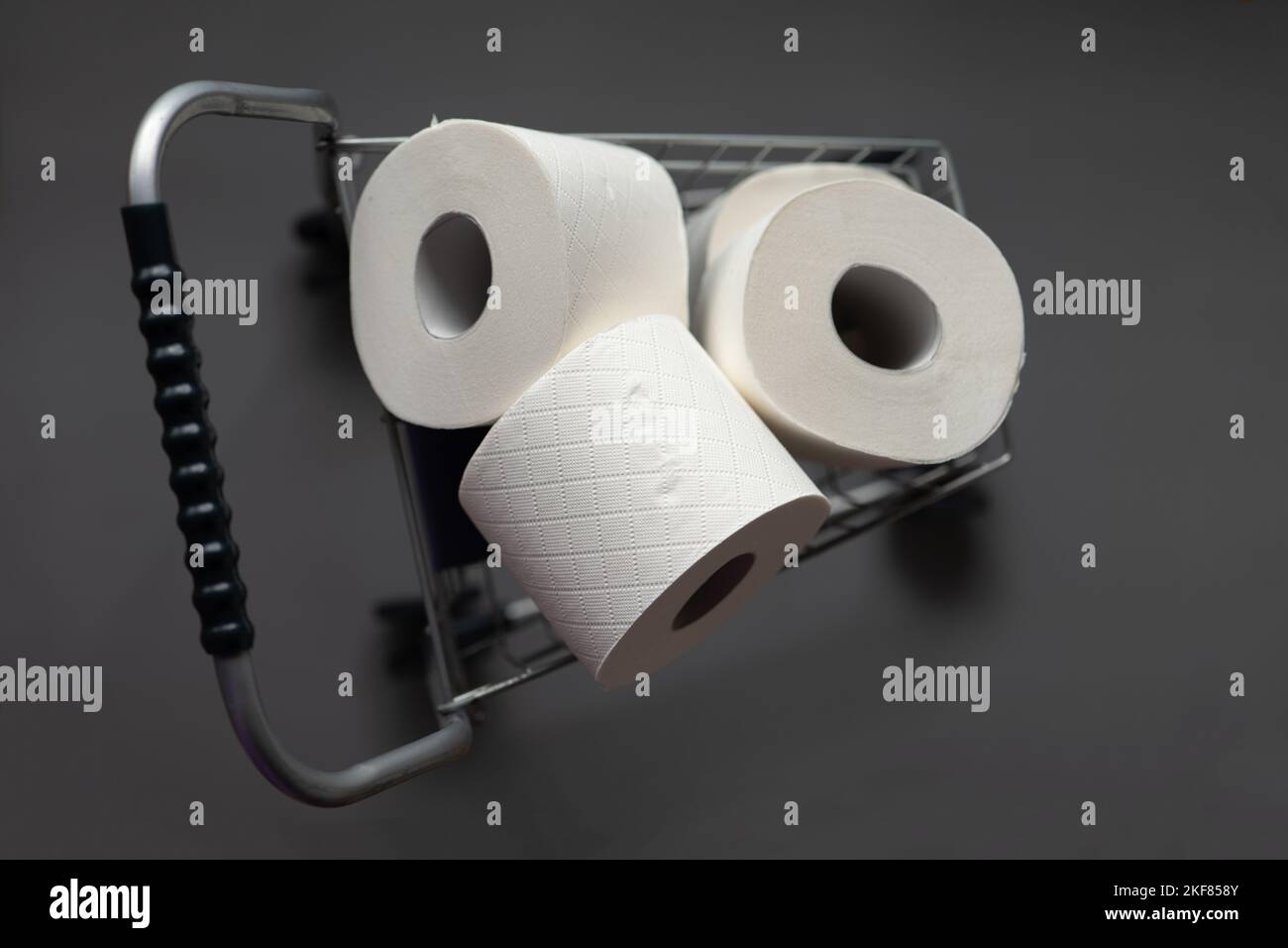 Toilet paper rolls in a supermarket trolley on a gray background