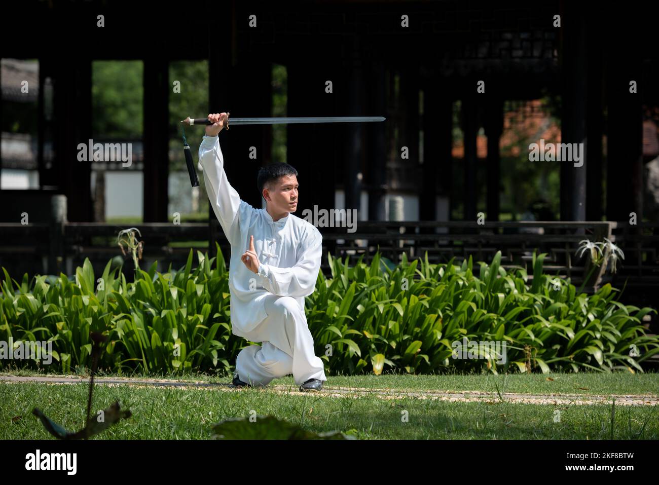Young man practicing traditional Tai Chi Sword, Tai Ji in the park for healthy, traditional
