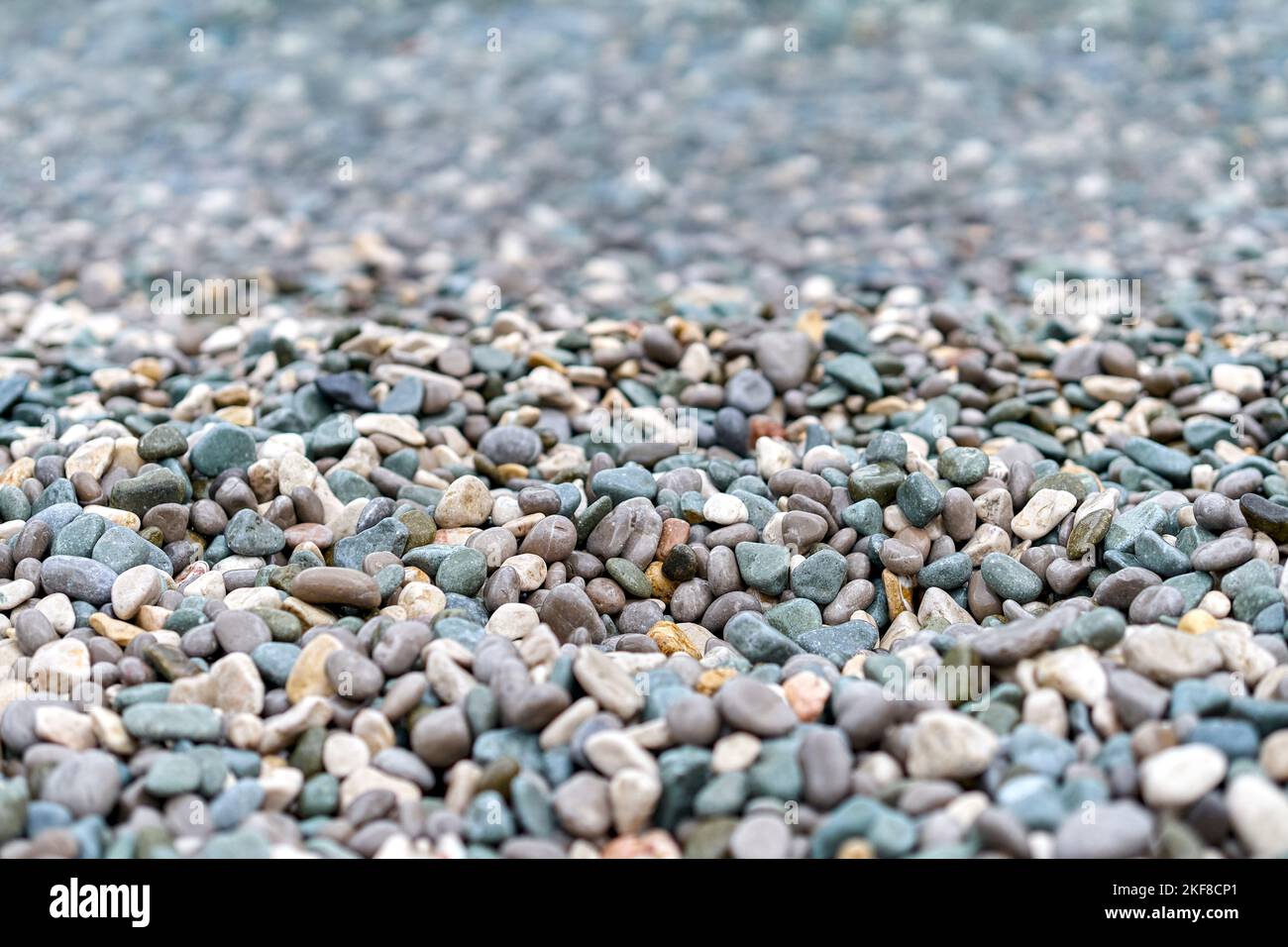 Crystal clean water washes pebbles lying on beach of sea. Wet pebbles
