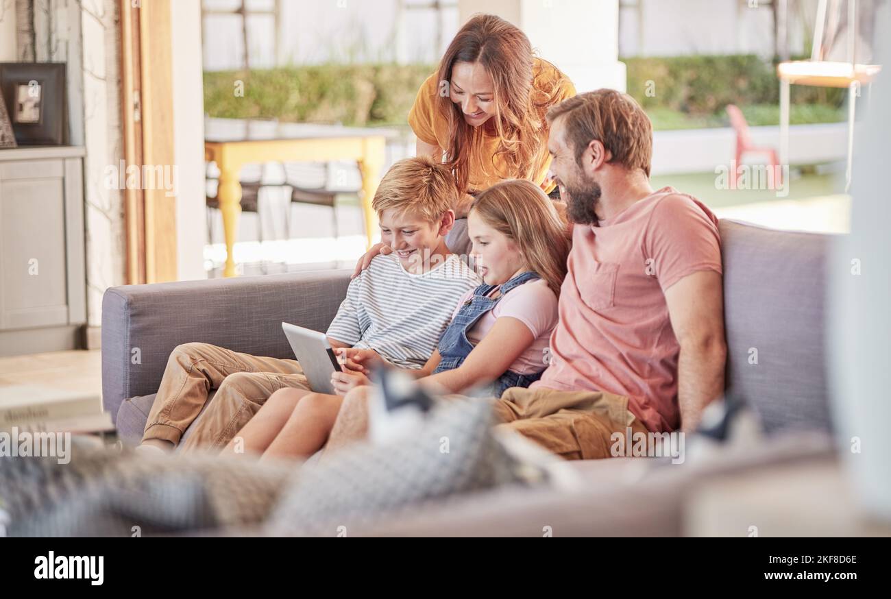 Parents, children and digital tablet on sofa in house or family home living room for movie, internet game or streaming. Smile, happy and bonding woman Stock Photo