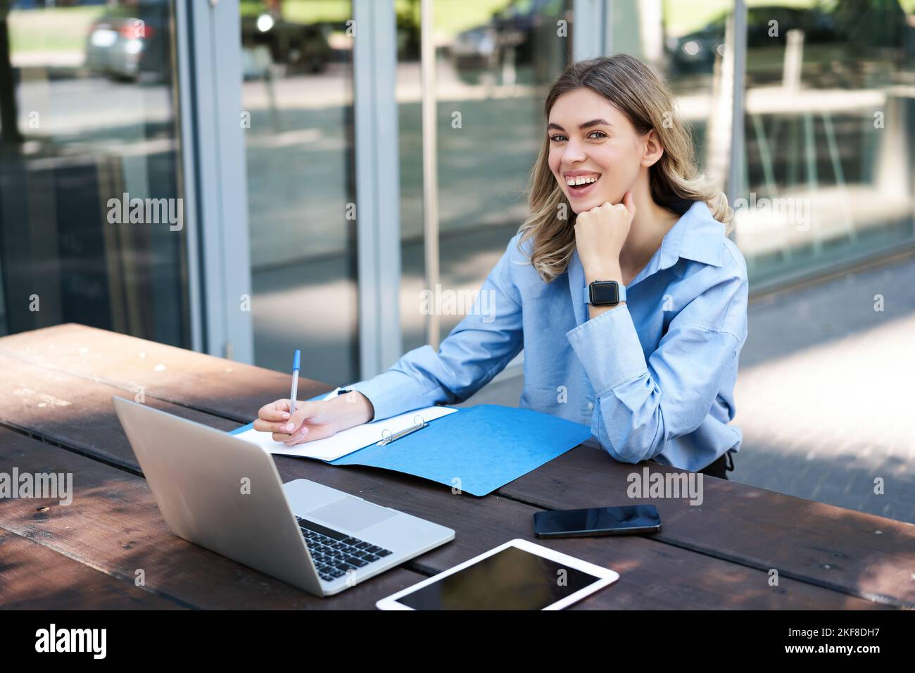 Happy saleswoman taking notes, working outdoors on fresh air, sitting ...