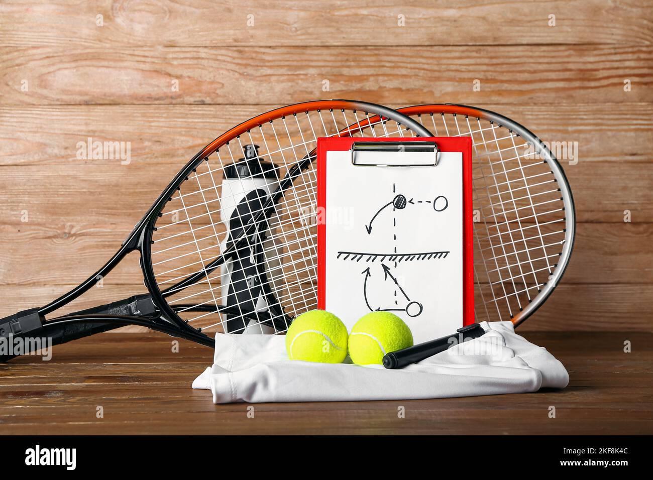 Clipboard with drawn scheme of tennis game, rackets, balls, skirt and bottle on wooden background Stock Photo
