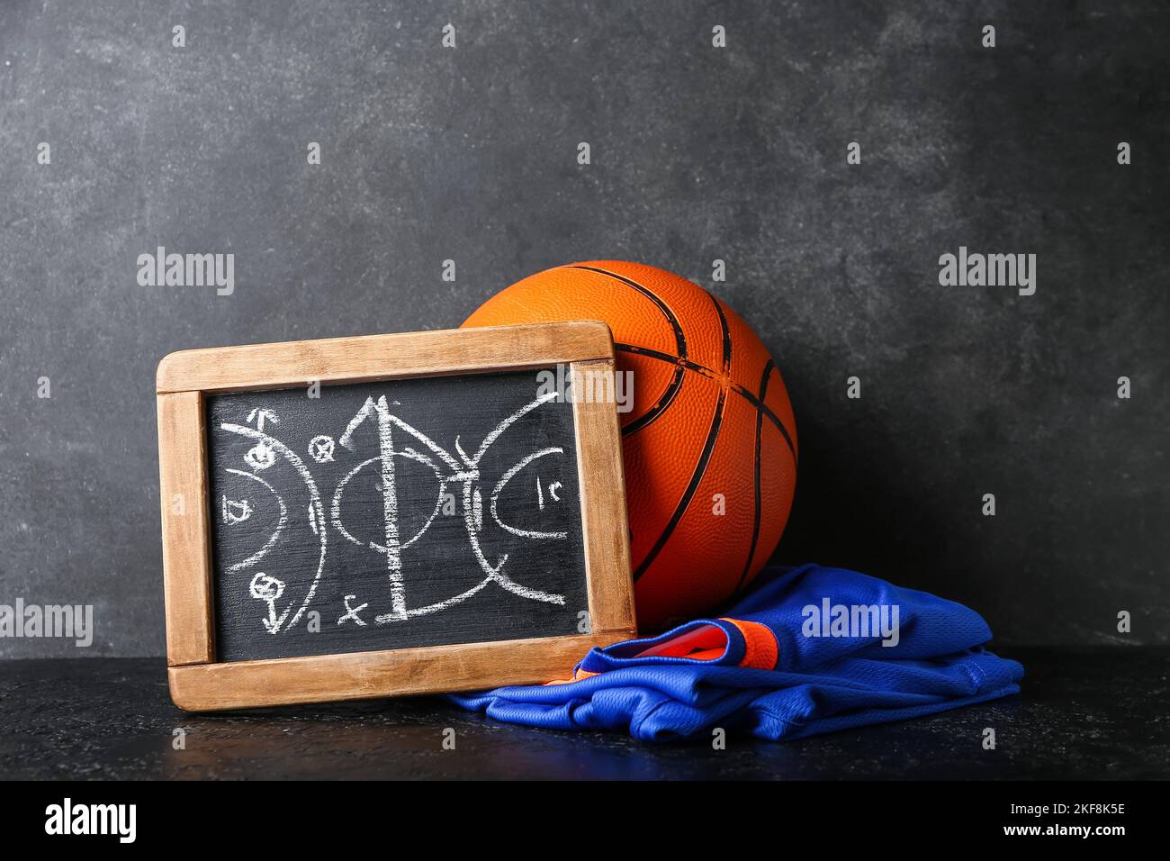Chalkboard with drawn scheme of basketball game, uniform and ball on