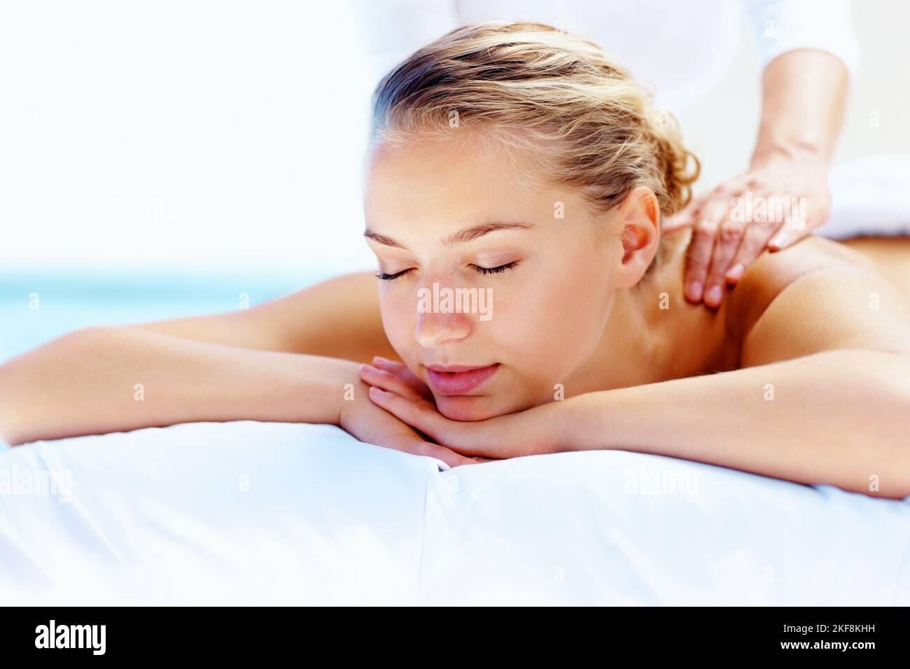 Young calm female receiving a shoulder massage at health spa. Young peaceful woman receiving a shoulder massage at health spa. Stock Photo