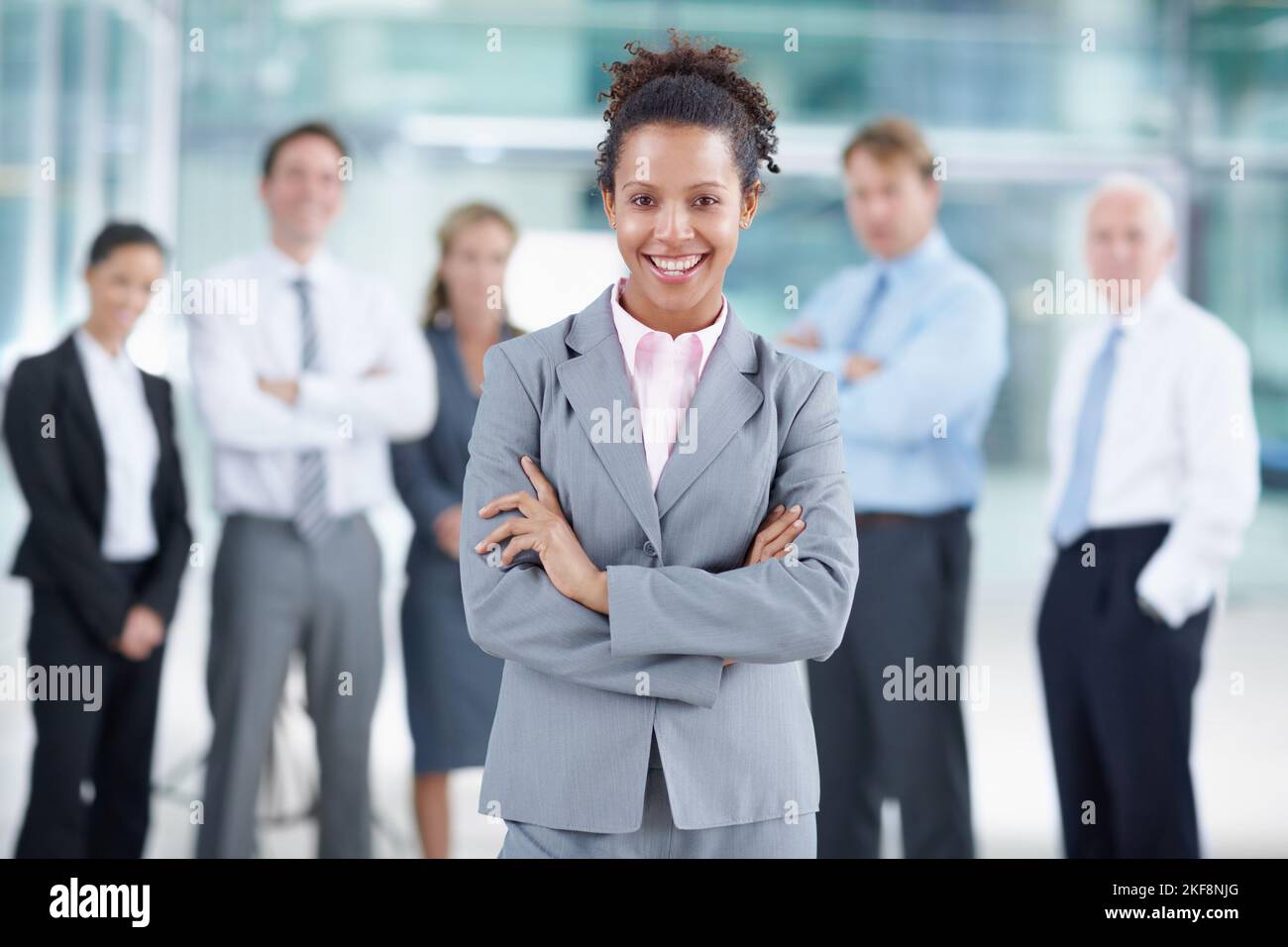 Shes climbing the corporate ladder with a smile. Smiling young African businesswoman standing with her coworkers behind her - portrait. Stock Photo