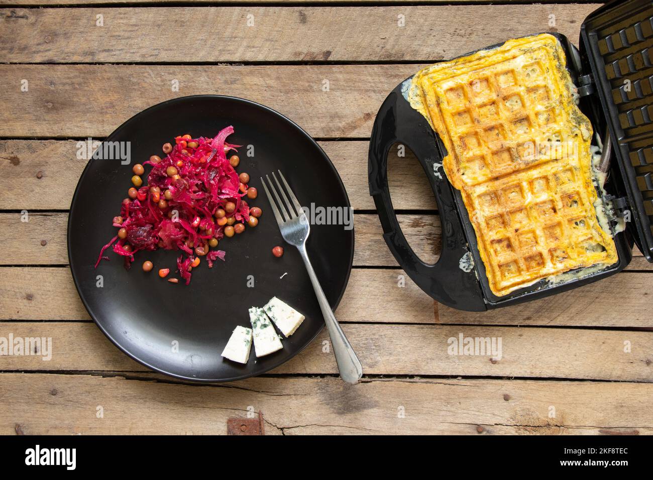 fry scrambled eggs with cheese and spices in a waffle iron on a wooden
