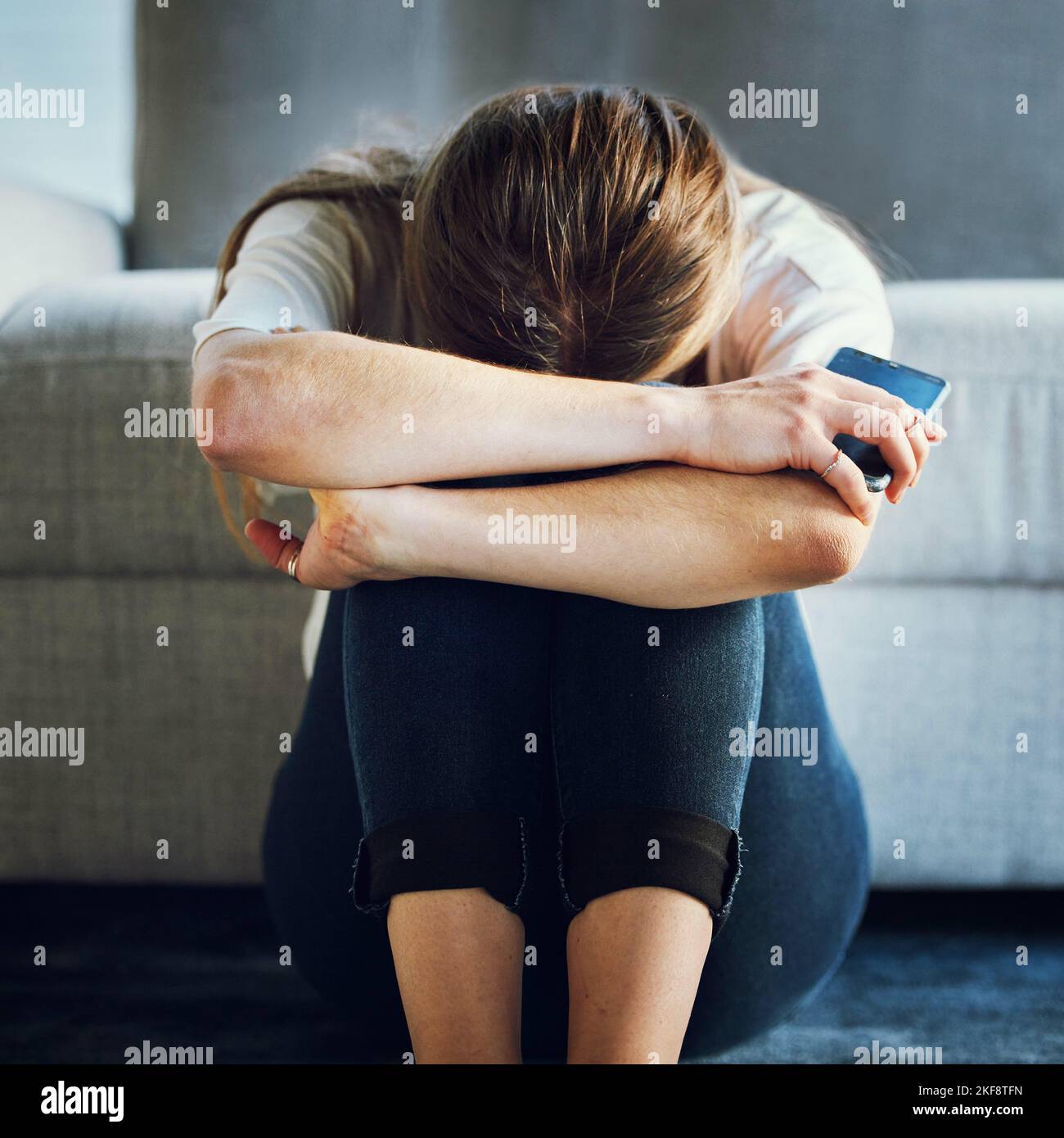 Sad, depression and woman with phone in living room home after break up message, cyber bullying victim or grief. Mental health, anxiety or depressed Stock Photo