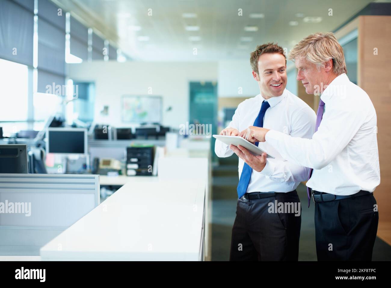 Executives using touchpad PC. Two business men discussing while using tablet PC. Stock Photo