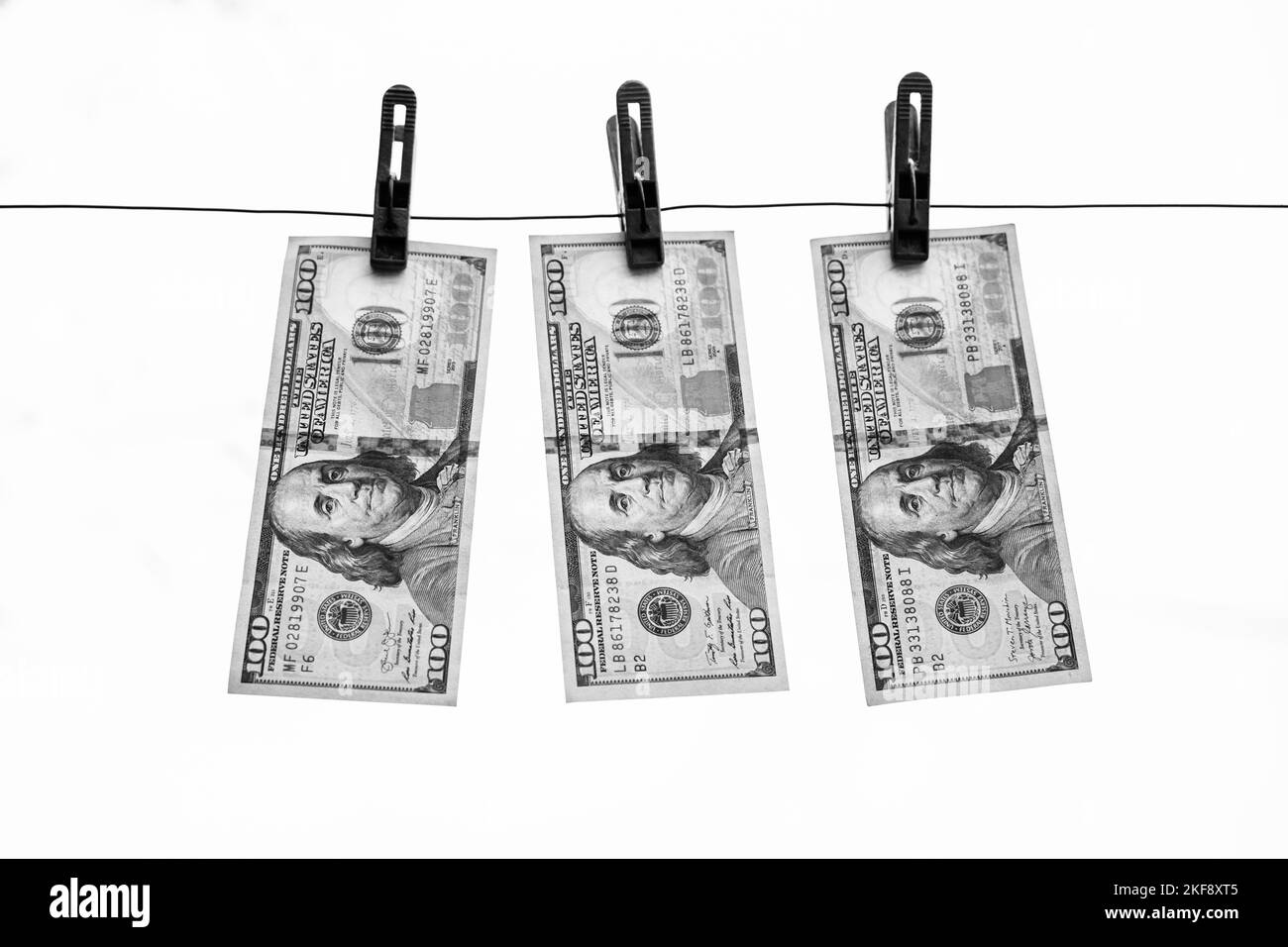 Black and white photo of dollars hanging on old clothespins on a white background Stock Photo