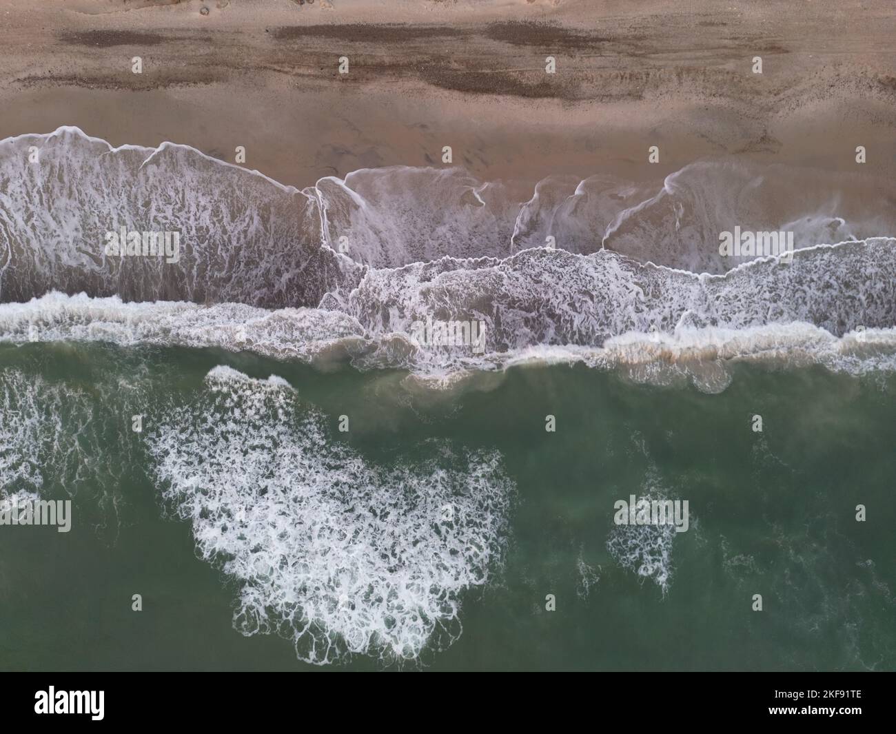 An aerial view of ocean waves with foam on a sandy beach Stock Photo ...