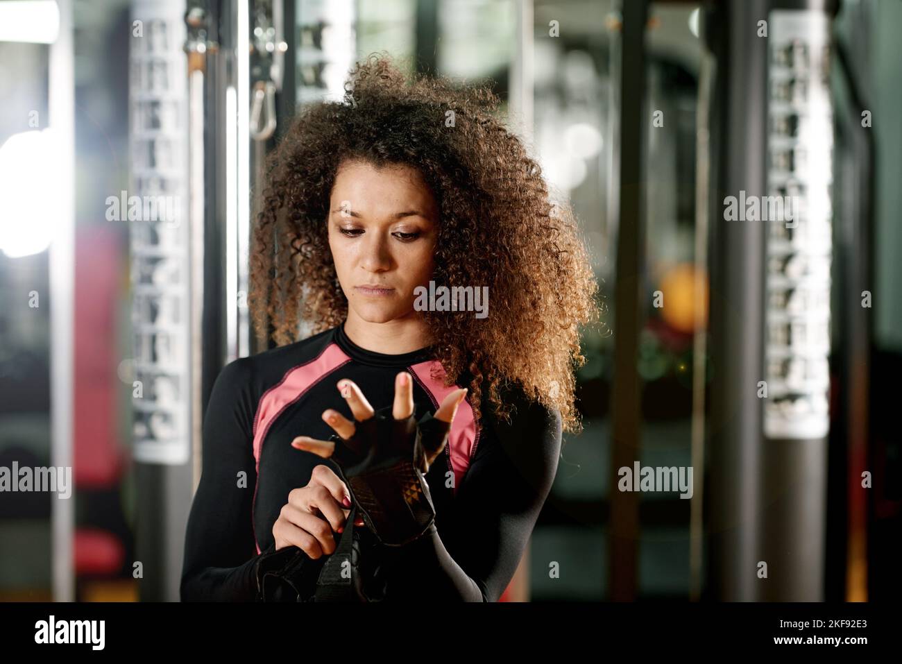Lets do this. a young woman putting on gloves for a workout at the gym