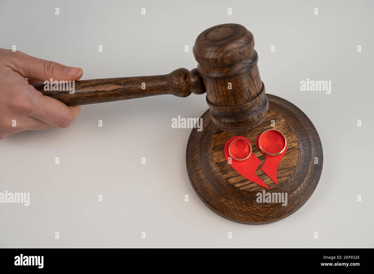 The judge hits the gavel on a broken heart and wedding rings Stock