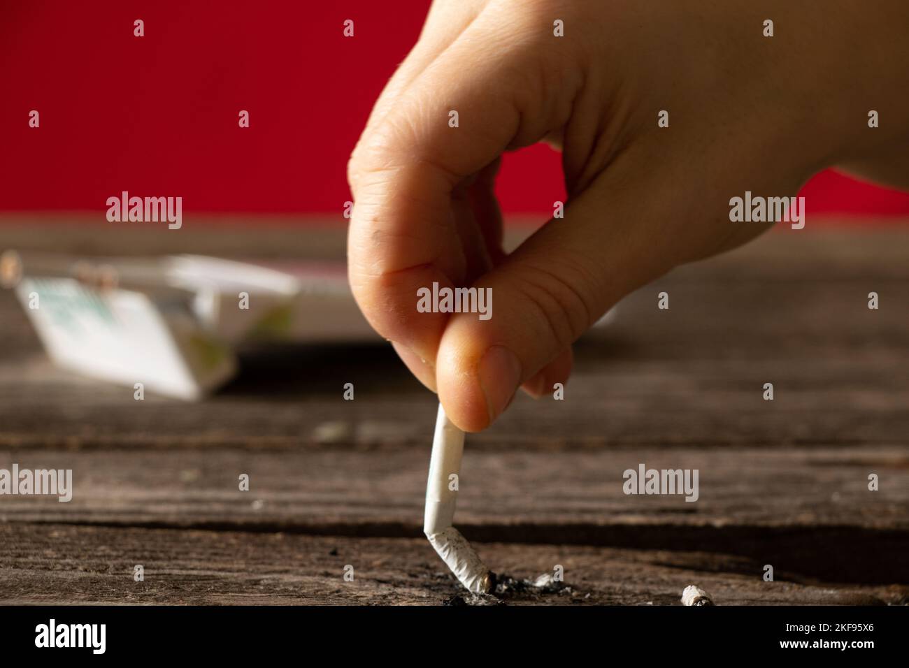 woman holding a cigarette at home at the table, smoking at home in the dark, nicotine and bad habit, cigarettes and cancer and smoking Stock Photo