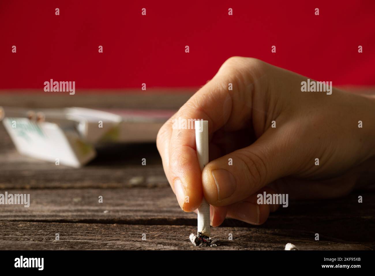 woman holding a cigarette at home at the table, smoking at home in the dark, nicotine and bad habit, cigarettes and cancer and smoking Stock Photo