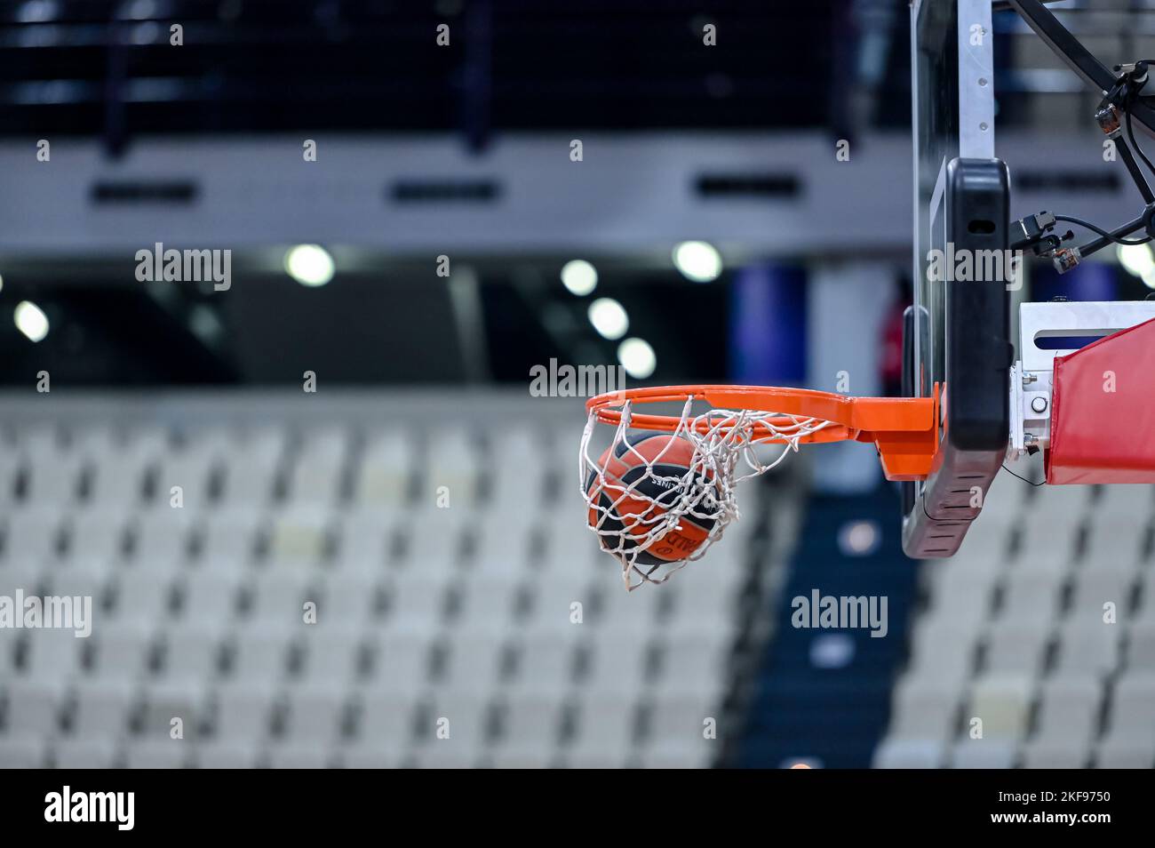 Basket ball entering the net in a basketball court with empty seats