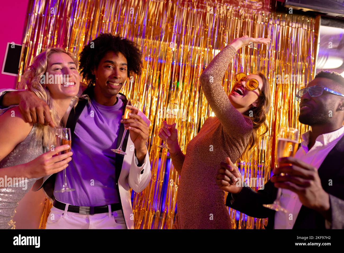 Two happy, diverse couples dancing and drinking champagne at a nightclub. Fun, drinking, going out, inclusivity and party concept. Stock Photo