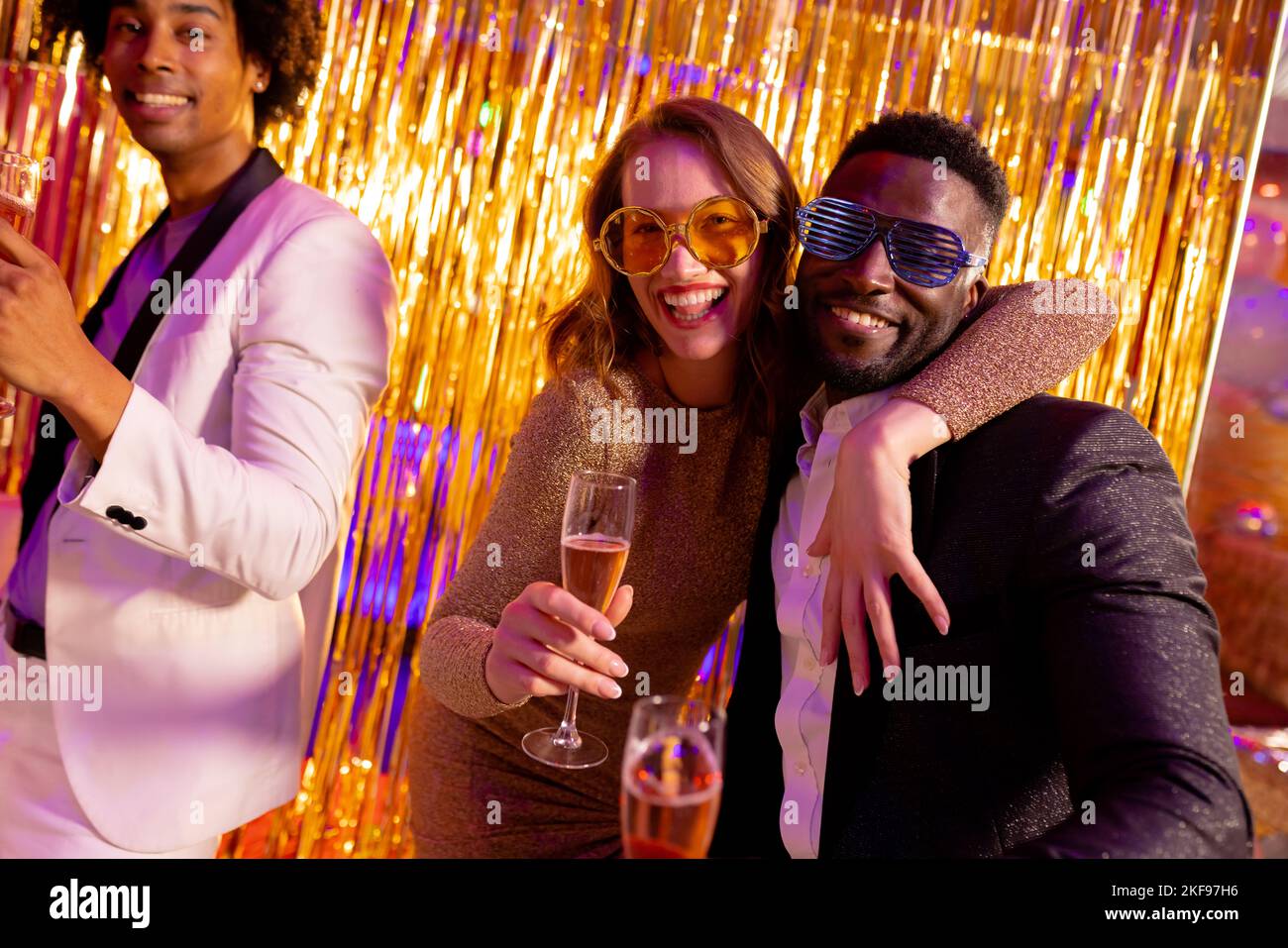 Happy, diverse couple and friend dancing and drinking champagne at a nightclub. Fun, drinking, going out, inclusivity and party concept. Stock Photo