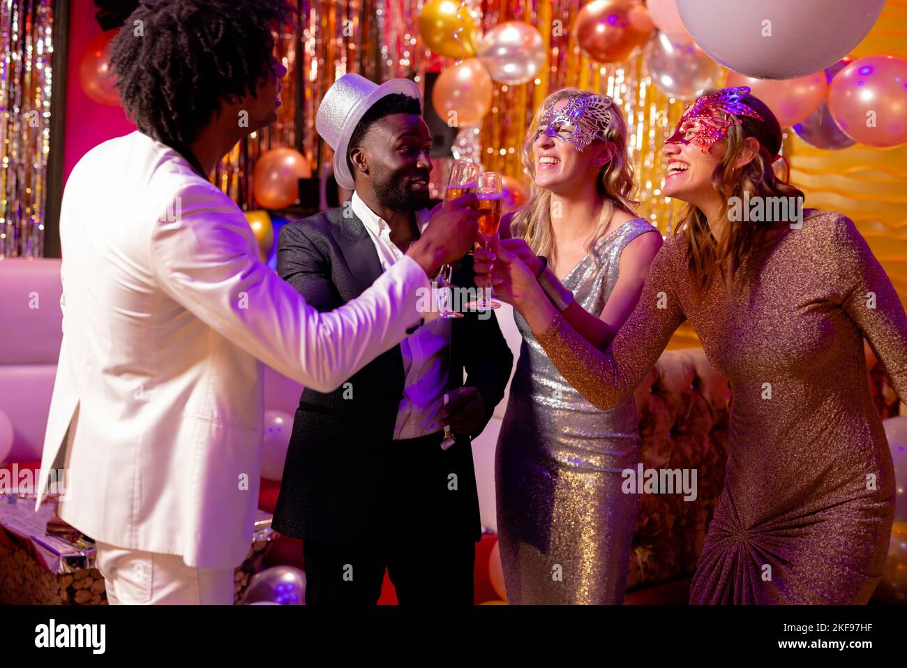 Four happy, diverse friends making a toast with glasses of champagne at a party in a nightclub. Fun, drinking, going out, inclusivity and party concep Stock Photo