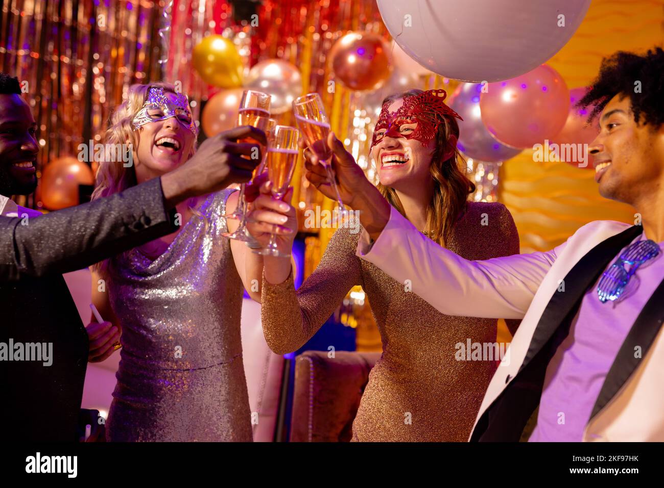 Four happy, diverse friends making a toast with glasses of champagne at a party in a nightclub. Fun, going out, inclusivity, celebrating and party con Stock Photo
