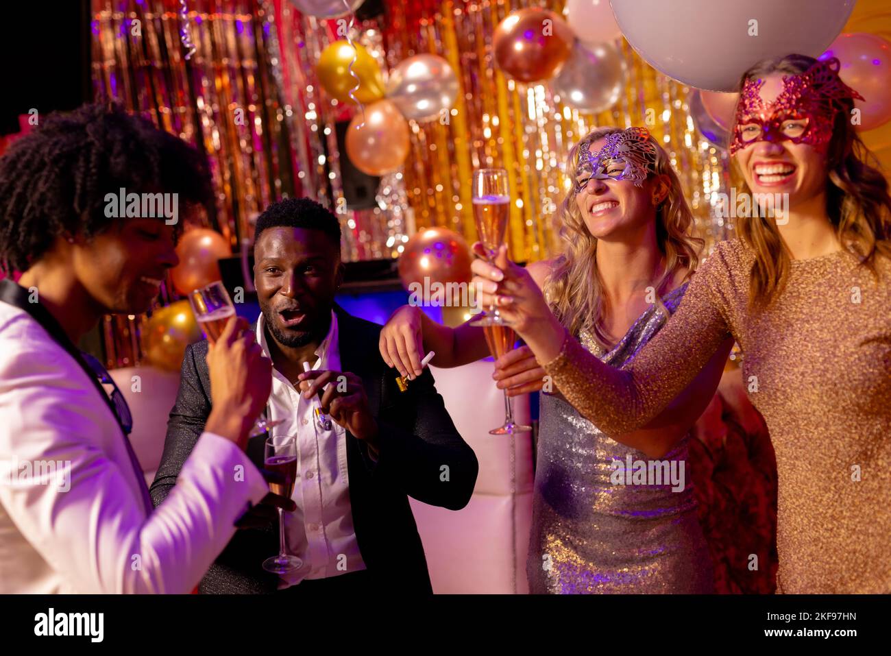 Four happy, diverse friends laughing and drinking glasses of champagne at a party in a nightclub. Fun, drinking, going out, inclusivity and party conc Stock Photo