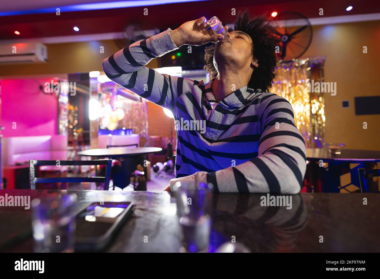 Drunk african american man sitting at the bar drinking shots in a bar Stock Photo