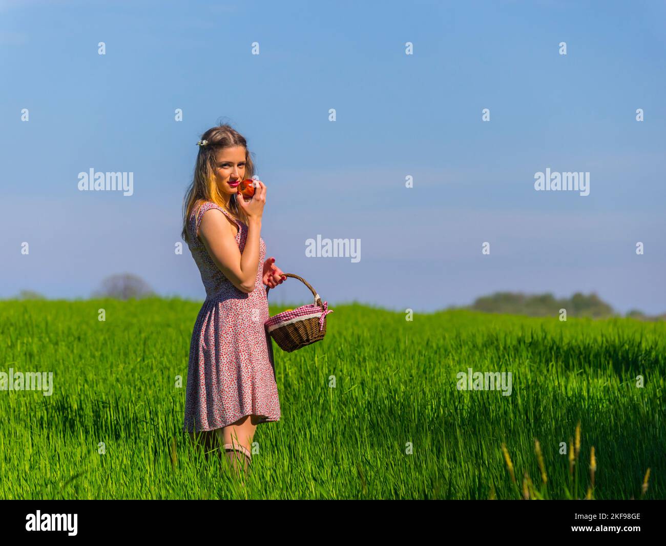 Runaway traveling young woman aka countrygirl eye eyes contact eyeshot against clear Blue sky three-quarter length copy-space copyspace eating apple Stock Photo