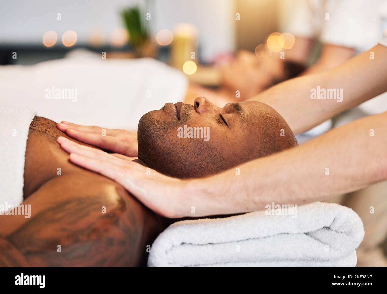 Massage, spa and black man with therapist hands, relax and skincare with zen, peace and wellness on bed. Physical therapy, healing and body therapy Stock Photo