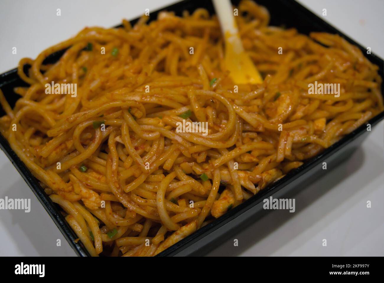 Spicy hakka noodles served in a disposable takeaway food container