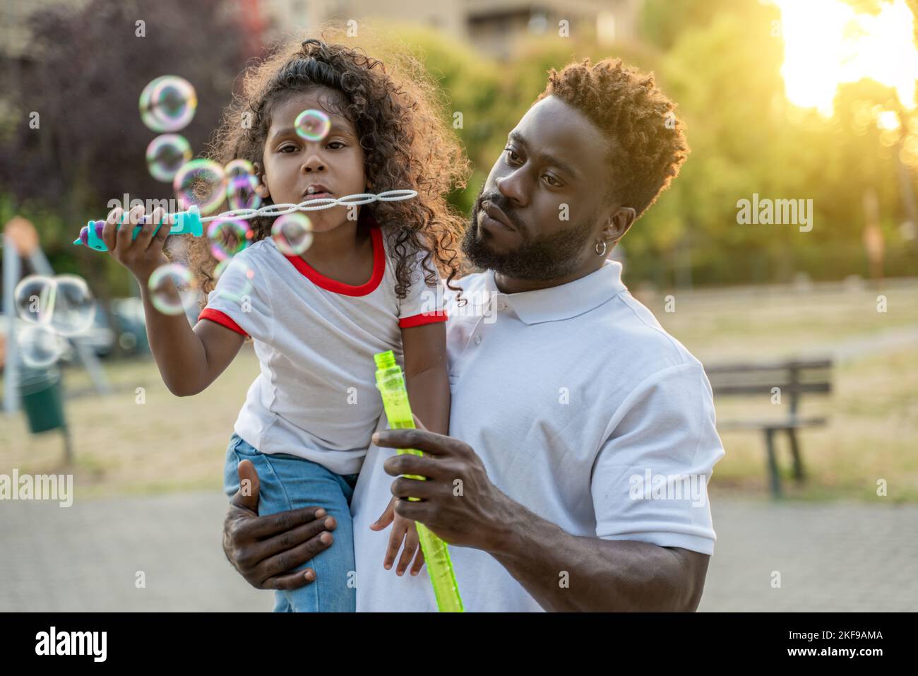 Little girl playing the bubble game in her father arms Stock Photo - Alamy