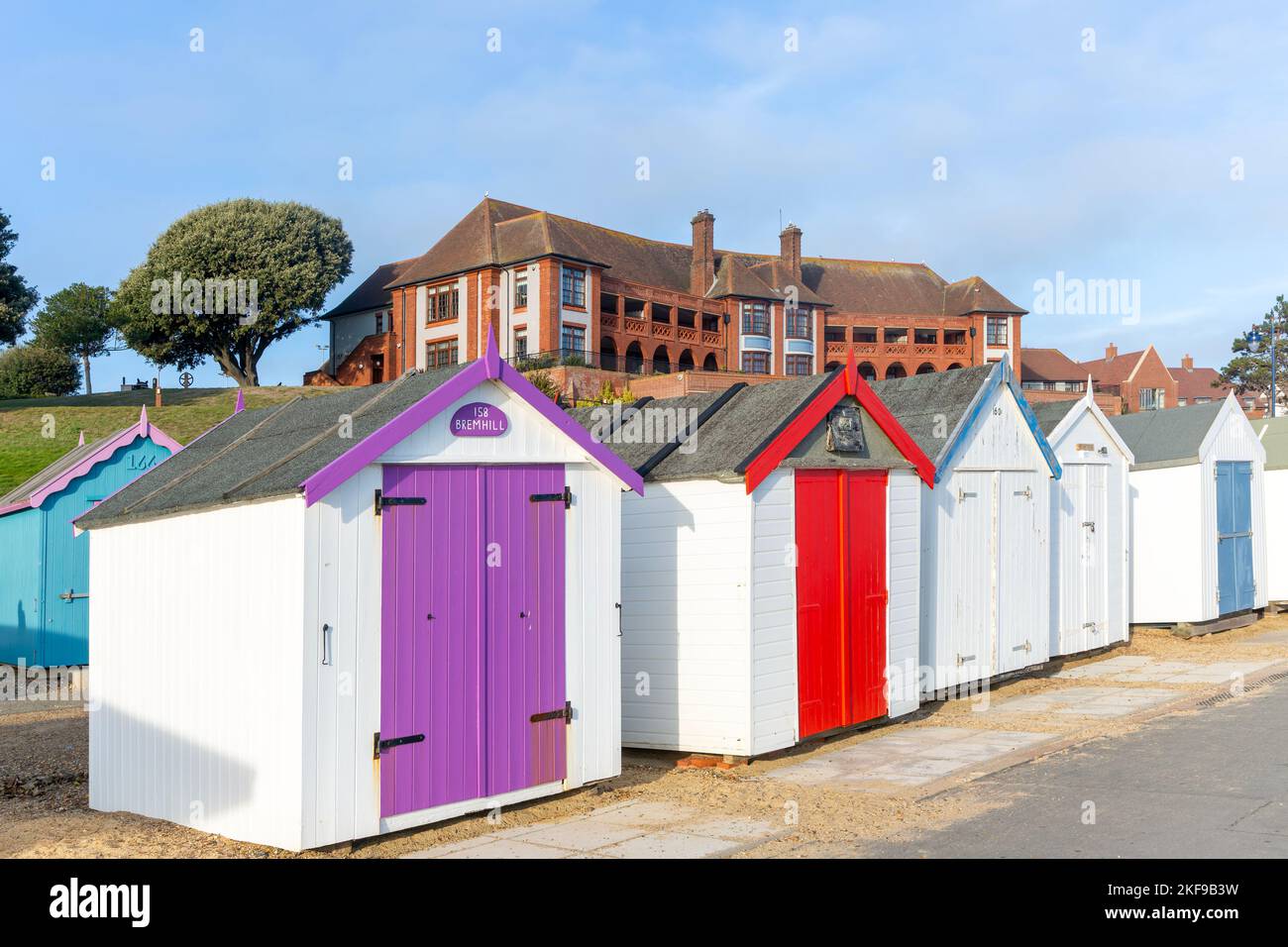 Colourful beach huts on seafront, Barlet Hospital building behind, Felixstowe, Suffolk, England, UK Stock Photo