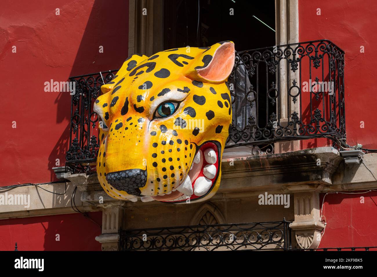 A large papiermache jaguar alebrije decoration over the street during the Day of the Dead