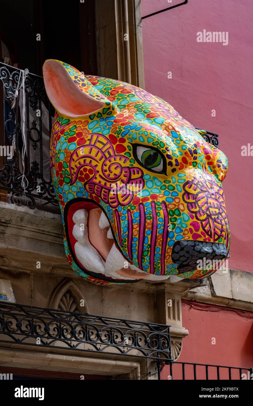 A large papiermache jaguar alebrije decoration over the street during the Day of the Dead