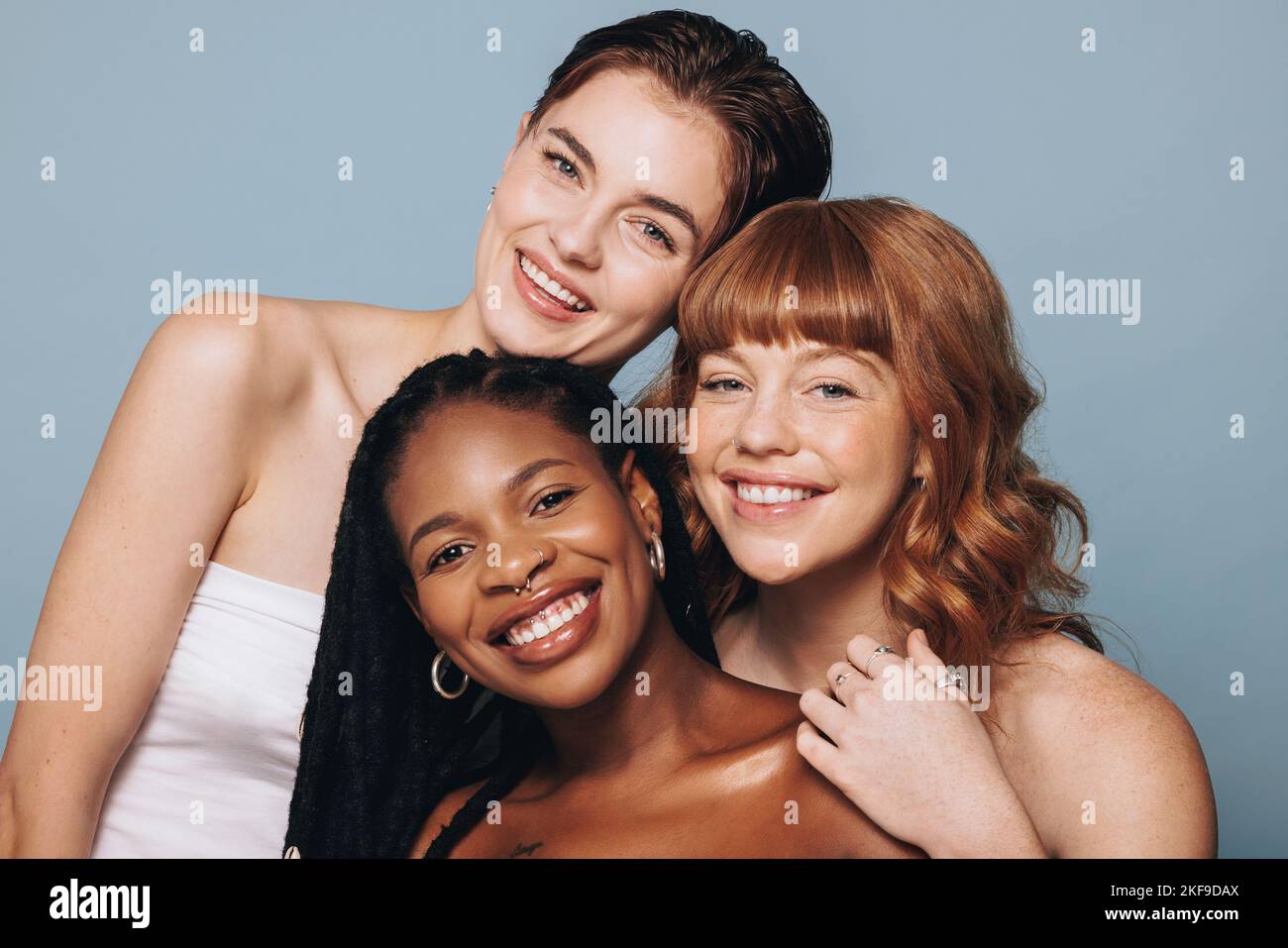Portrait of women with different skin tones smiling at the camera in a studio. Group of happy young women feeling comfortable in their own skin. Three Stock Photo