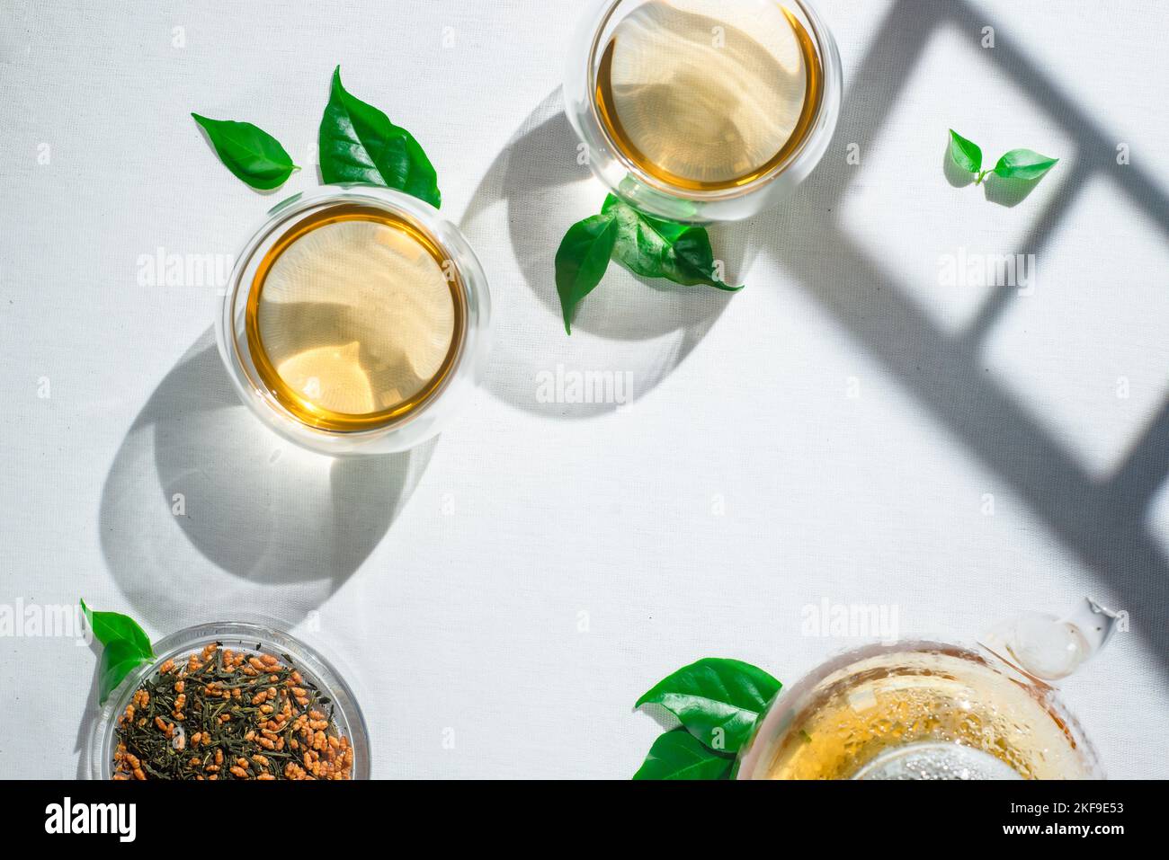 Genmaicha green tea, Torii gates shadow, white tablecloth, glass teapot Stock Photo