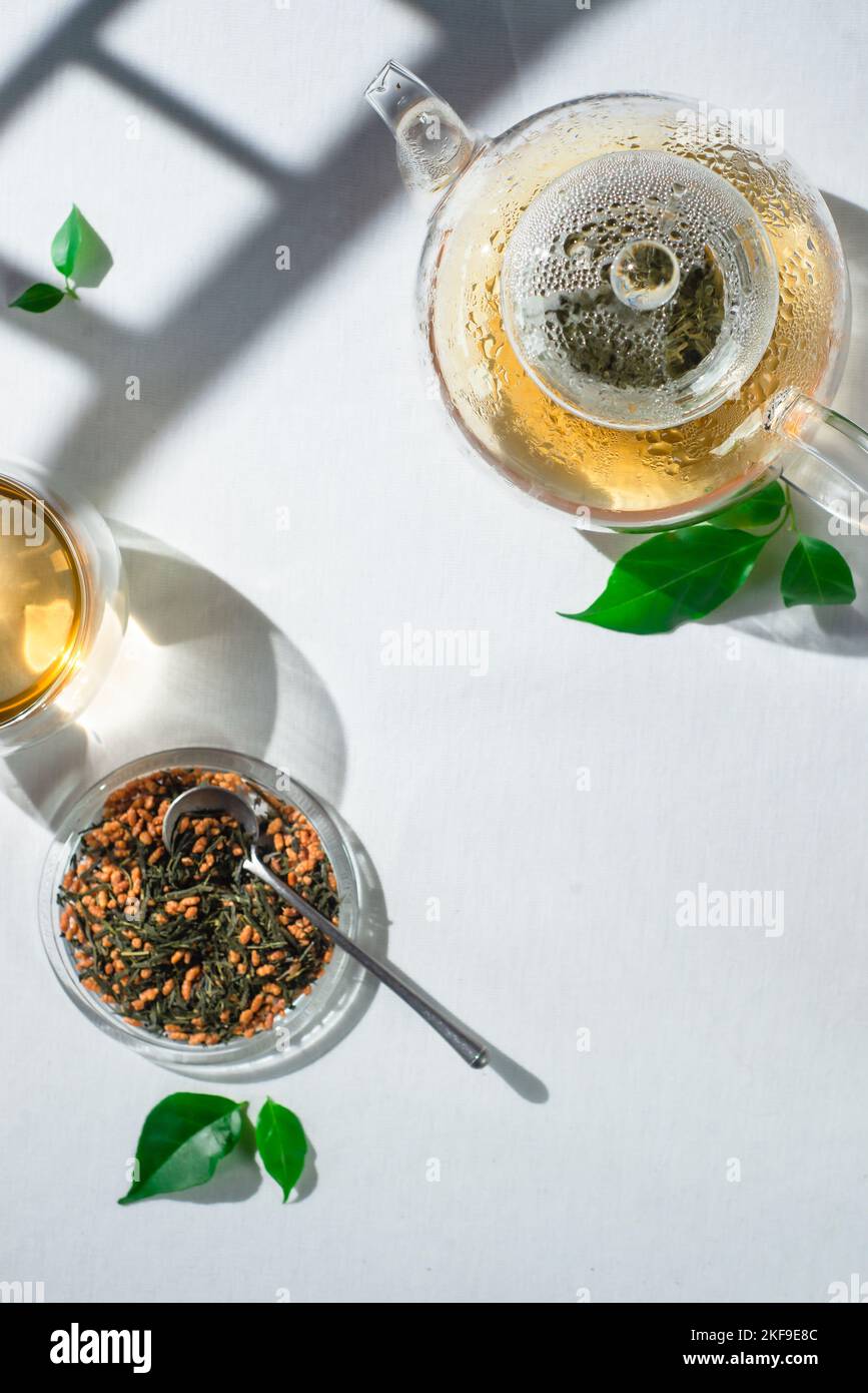 Genmaicha green tea, Torii gates shadow, white tablecloth, glass teapot Stock Photo