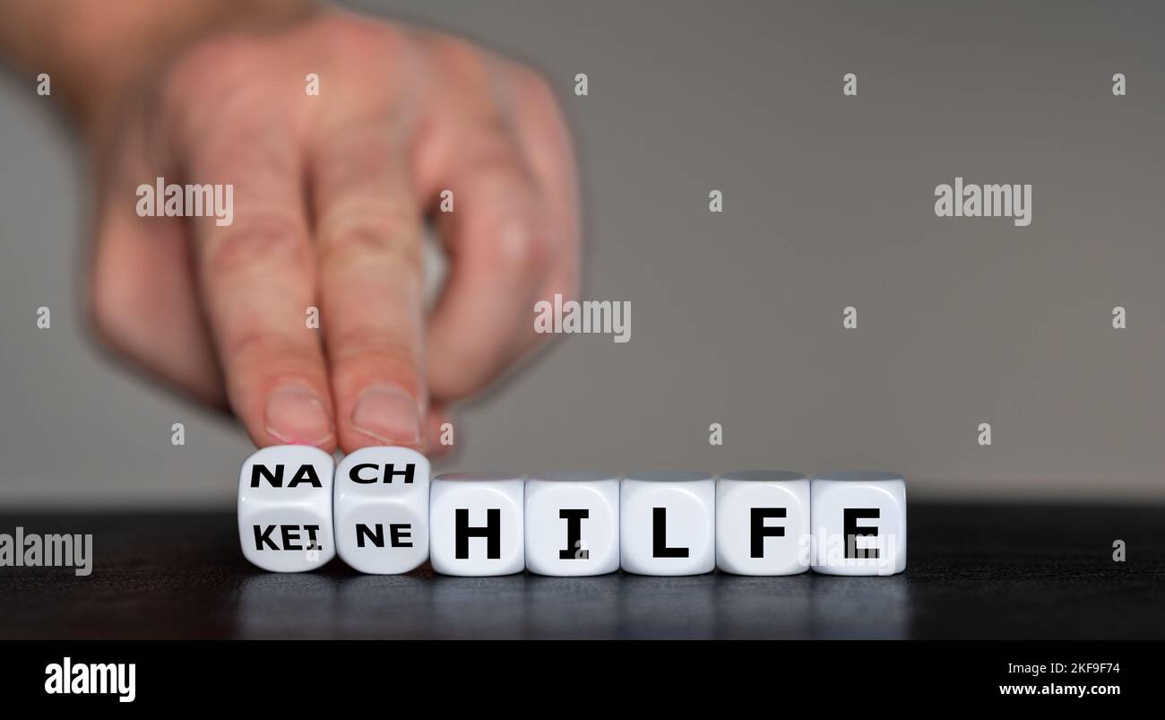 Hand turns dice and changes the German expression 'keine Hilfe' (no help) to 'Nachhilfe' (private lessons). Stock Photo