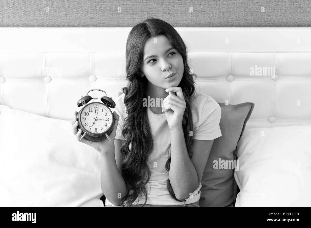 You never know when your time is coming. Kid look thoughtful with alarm clock. Using time creatively Stock Photo