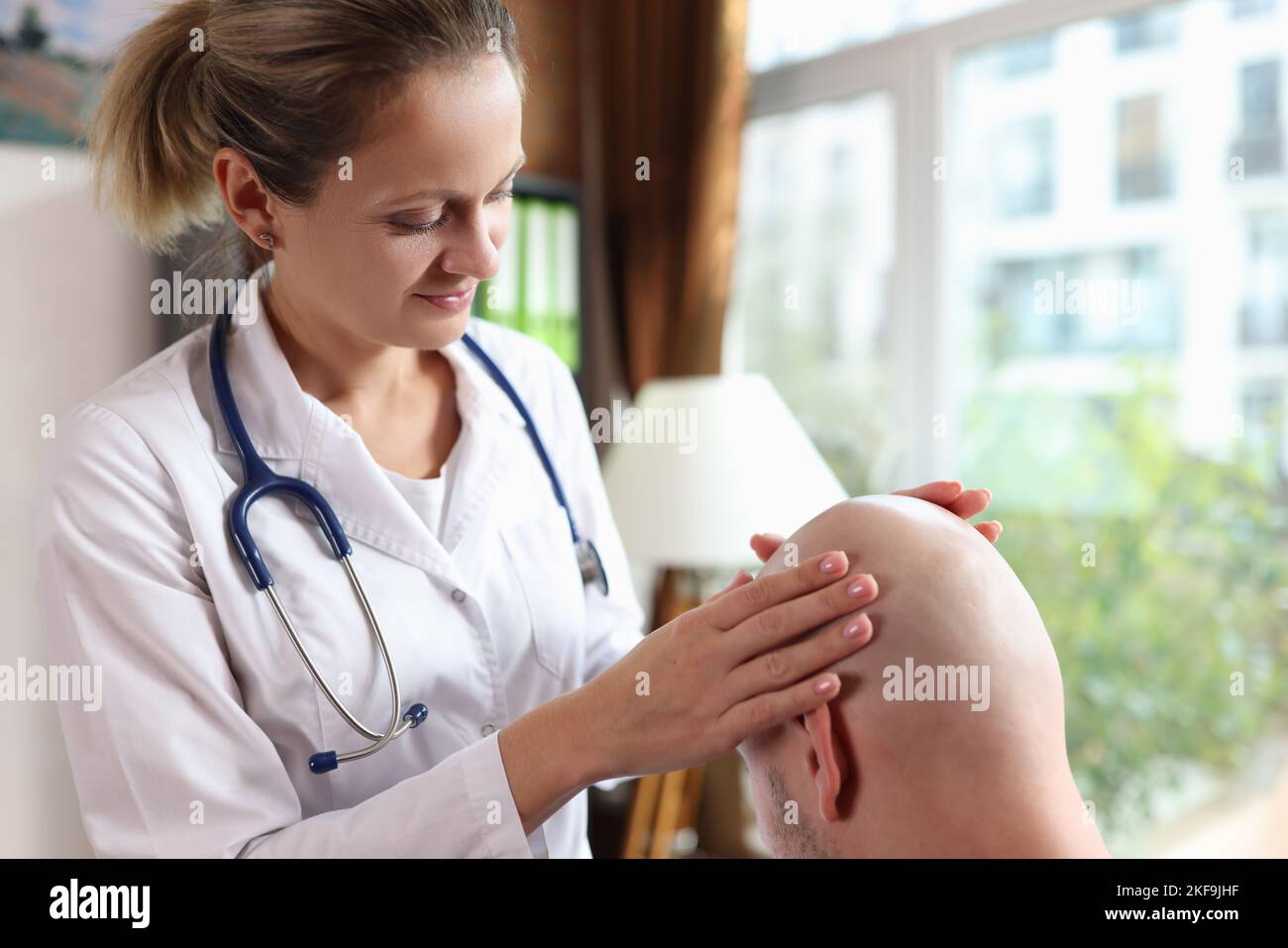 Female doctor examines male patient with hair loss problem at consultation in clinic. Stock Photo