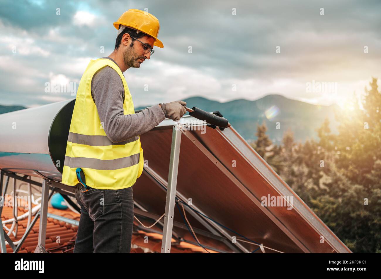 Man works on renewable energy system with solar panel for hot water Stock Photo