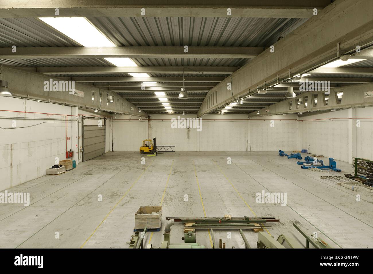 A large empty industrial warehouse with concrete floors and skylights on the roofs Stock Photo