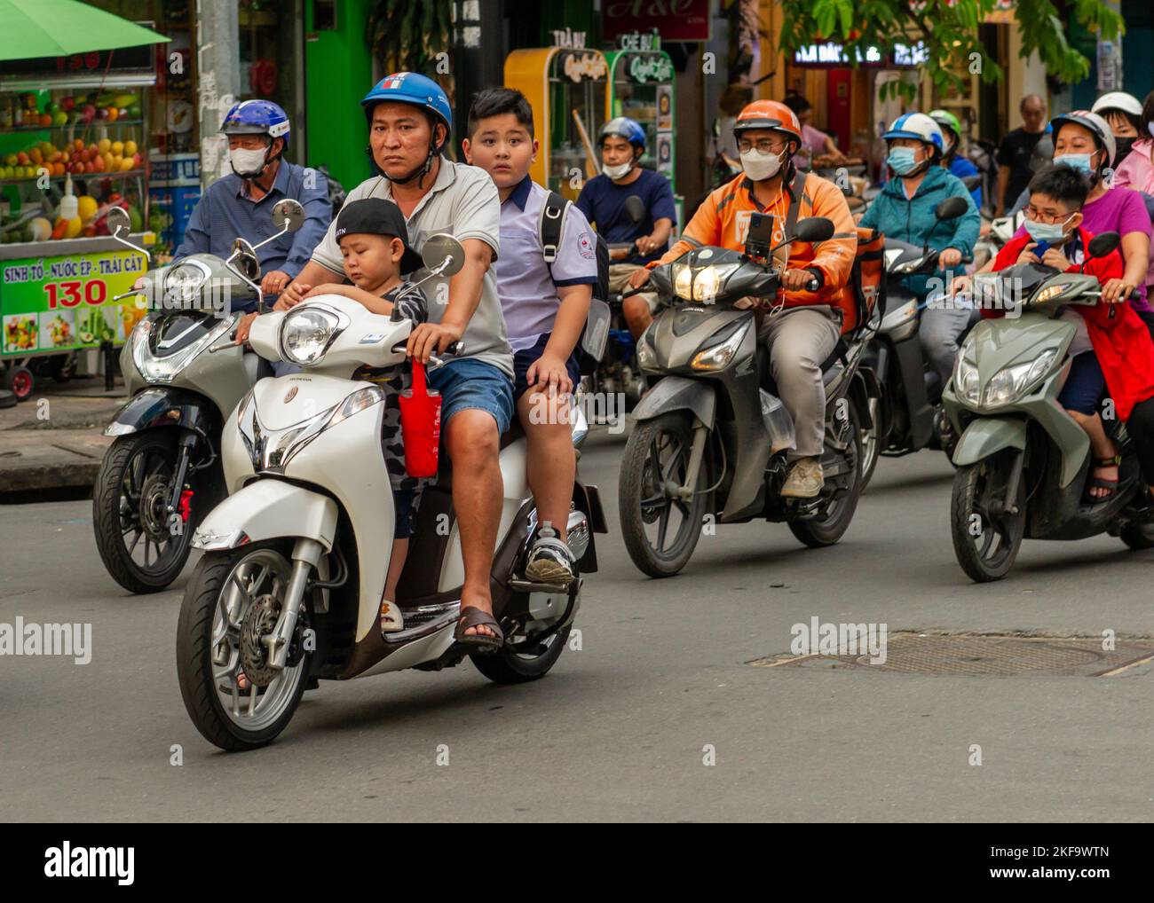 Saigon Street Life.  A father does the school run with his two kids. A rush hour motorcycle swarm in Ho Chi Minh City Stock Photo