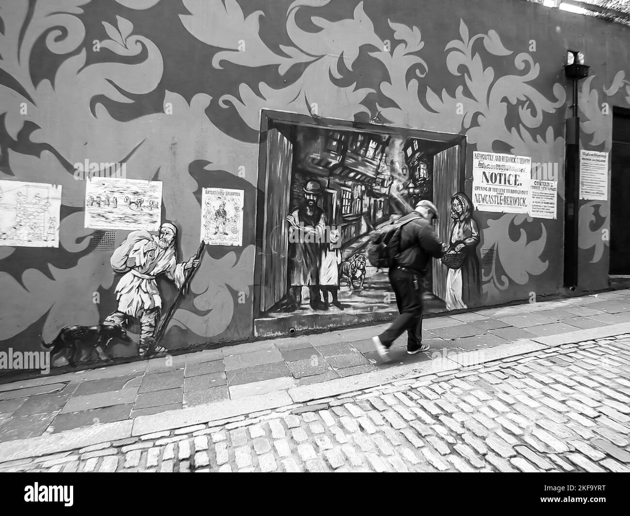 A grayscale side view of senior man walking on the street with street art on the walls Stock