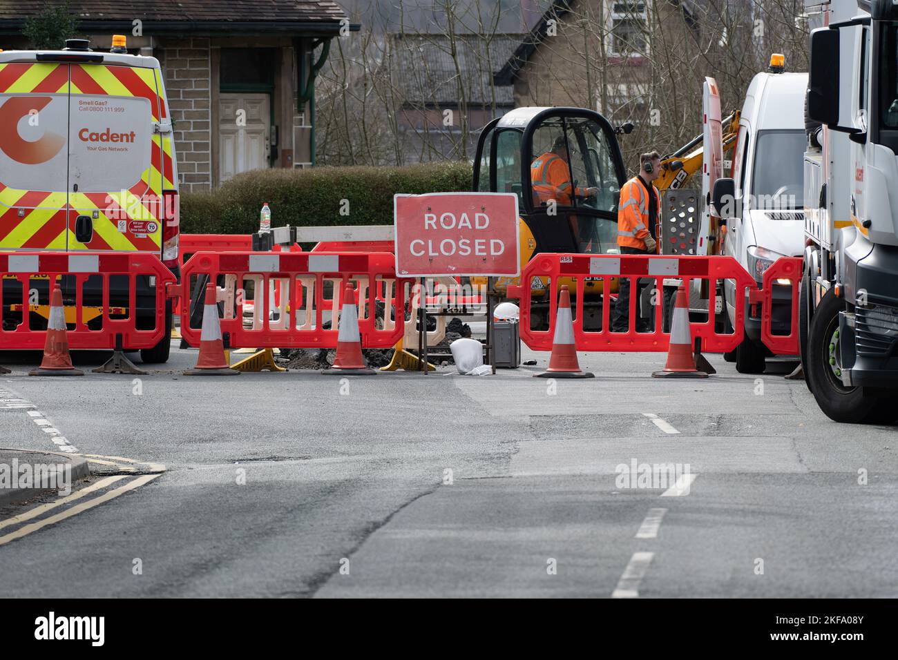 Road closed with men at work on digger digging up the road. Road Works