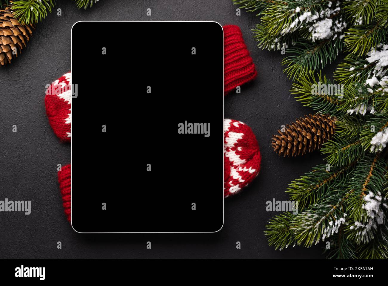 Tablet with blank screen over winter mittens and Christmas decor. Xmas device screen template Stock Photo