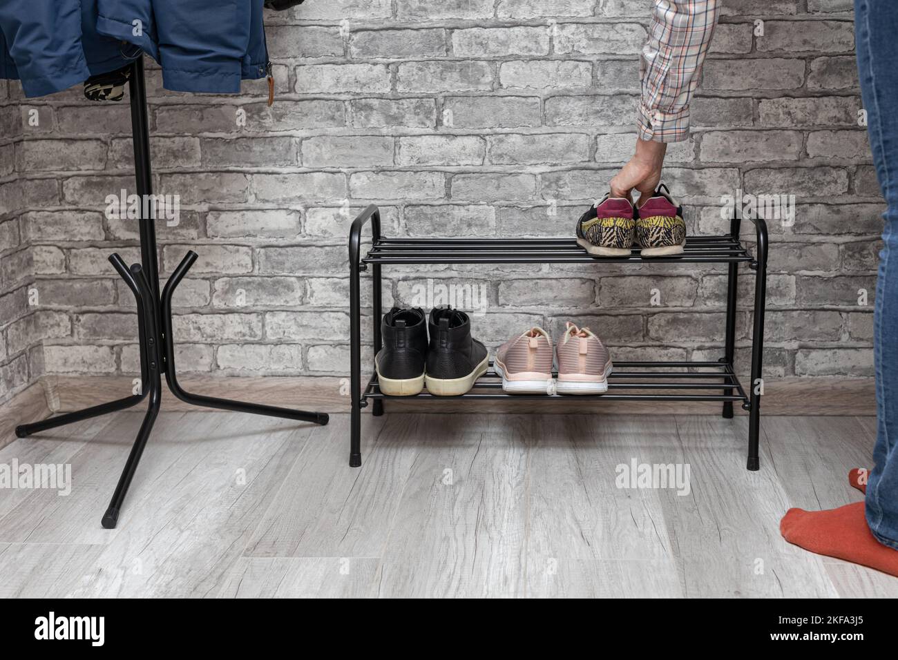 a man puts shoes on a shoe rack in the hallway. man chooses shoes Stock Photo